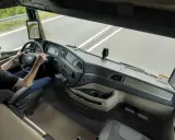Conductor en un camión moderno sin retrovisores, usando pantallas digitales para ver el camino.