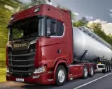 Camión cisterna Scania 800 CV de color rojo brillante, circulando por una carretera rodeada de árboles.