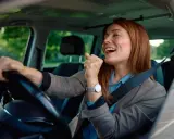 Mujer sonríe y canta al volante, feliz de conducir en España con su carnet de conducir ucraniano.