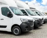 Fila de furgonetas blancas listas para la entrega. El modelo dgt n1 es el primero de la fila, con un diseño moderno y robusto.