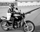Motociclista con casco y chaleco reflectante en una Honda, preparándose para obtener el carnet de moto grande.