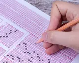 Mano con lápiz completando un examen de respuestas múltiples. ¿Cuántas preguntas son el examen de conducir?