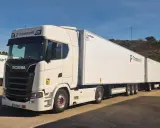 Un mega camión blanco Scania con dos remolques largos de Transmarfil, listo para transportar mercancías.