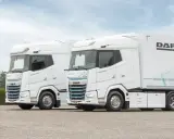 Dos camiones DAF XG Plus eléctricos, blancos, con el interior visible. Uno lleva un remolque DAF.