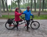 Pareja feliz en un eje tandem triaxial, disfrutando de un paseo en bicicleta por el parque.
