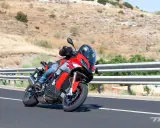 Motociclista en moto deportiva roja y gris en carretera. ¿Cuánto se tarda en sacar el carnet de moto?