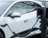 Coche eléctrico blanco cargando. El poste de carga muestra 3.57 kW, cumpliendo el reglamento AFIR para la infraestructura de energía.