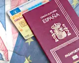 Pasaporte español y carnet de conducir básico sobre banderas de Reino Unido y Unión Europea.