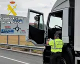 Agente de la Guardia Civil revisa documentación de un camión. Se puede conducir un camión sin tarjeta de transporte si se cumplen ciertos requisitos.