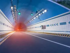 El efecto túnel se percibe al entrar en este túnel vial iluminado, con luces verdes y un resplandor rojo al fondo.