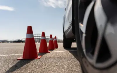 Conos naranjas marcan la zona f para el carnet C. Un coche se acerca, listo para la maniobra.