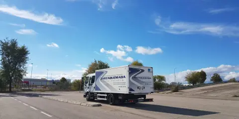 Camión de autoescuela Zarzaquemada, listo para obtener el carnet C+E. Cielo azul con nubes.