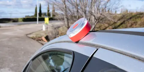 Baliza de emergencia roja y blanca en el techo de un coche plateado, lista para evitar una multa.