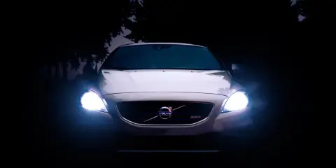Volvo blanco con luces encendidas en la oscuridad.