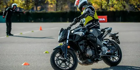 Motociclista con equipo de protección en una pista de examen con conos.