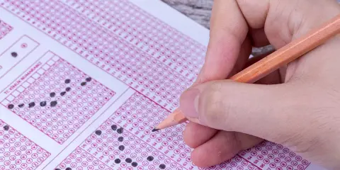 Mano con lápiz completando un examen de respuestas múltiples. ¿Cuántas preguntas son el examen de conducir?