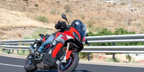 Motociclista en moto deportiva roja y gris en carretera. ¿Cuánto se tarda en sacar el carnet de moto?