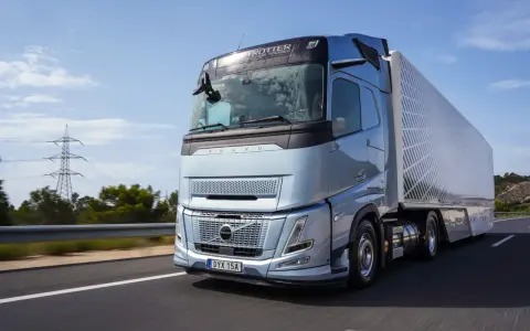 El nuevo Volvo FH Aero, un camión azul metálico, avanza por una carretera soleada, listo para transportar cargas con su diseño aerodinámico.