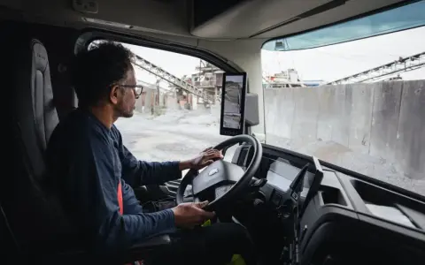 Interior de un camion Volvo. Un hombre con gafas conduce, observando las cámaras de visión.