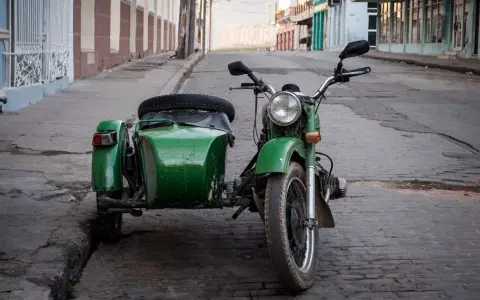 Motocicleta verde con sidecar, lista para recorrer calles empedradas. Un clásico que aún recibe permiso a motocicletas con sidecar.