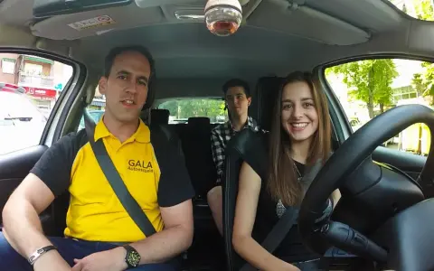 Instructor de autoescuela sonríe junto a dos alumnos en un coche. ¡Listos para el turismo y el aprendizaje!