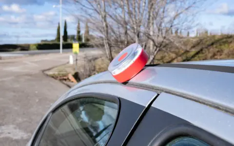 Baliza de emergencia roja y blanca en el techo de un coche plateado, lista para evitar una multa.