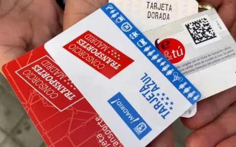 Manos sostienen varias tarjetas de transporte de Madrid, incluyendo la Tarjeta Dorada y la Tarjeta Azul, mostrando algunas excepciones de transporte.