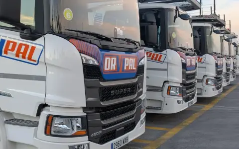 Fila de camiones Scania Super blancos, listos para la carretera.