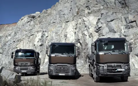 Tres robustos renault trucks modelos posan ante un imponente acantilado de cantera, listos para el trabajo pesado.