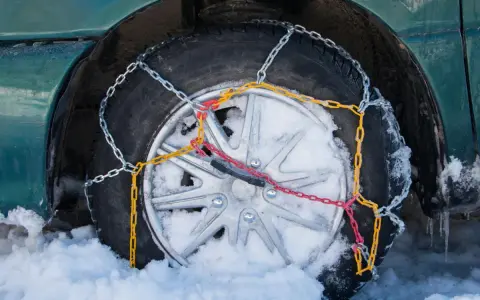 Neumático con cadenas de nieve instaladas, mostrando cómo se ponen las cadenas de nieve para circular en condiciones invernales.