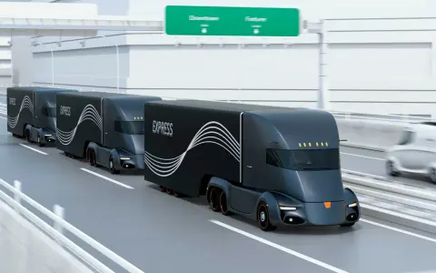 Tren de camiones del futuro, negros y aerodinámicos, circulando por una autopista.