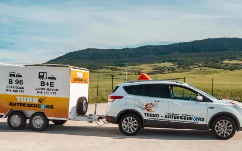 Coche blanco de autoescuela Turbo con remolque. Preparados para obtener el carnet B+E.