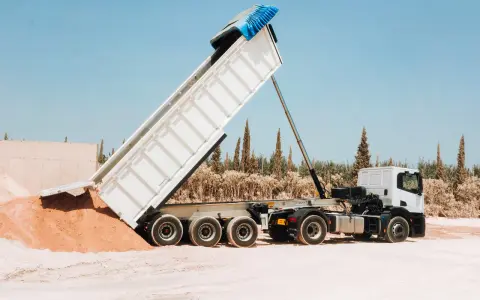 Camión volquete descargando arena. La distancia entre ejes de los camiones es clave para su maniobrabilidad en terrenos difíciles.