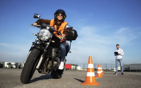 Mujer sonriente practica en circuito cerrado a1, con conos naranjas y un instructor al fondo.