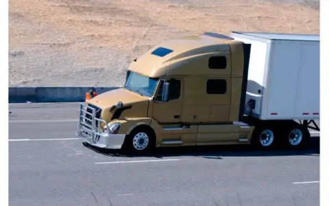 Camión dorado de 40 toneladas en carretera, transportando carga en su remolque blanco.
