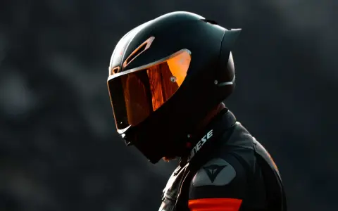 Motociclista con casco negro y visor naranja, listo para la acción. El uso obligatorio de casco es clave para la seguridad.