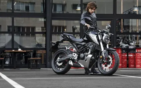 Joven con chaqueta de cuero junto a una moto negra, listo para obtener su a1 permiso de conducir.