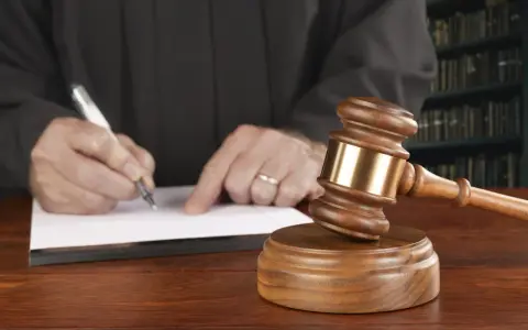 Juez firma sentencia que implica retirada carnet de conducir por curso. Martillo de juez y libros de derecho.