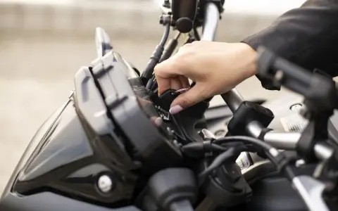 Mano insertando la llave de contacto en una moto, preparándose para el carnet A2.