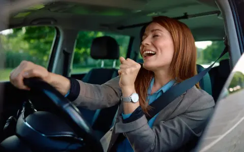 Mujer sonríe y canta al volante, feliz de conducir en España con su carnet de conducir ucraniano.