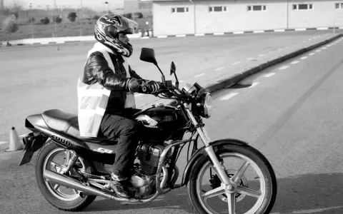 Motociclista con casco y chaleco reflectante en una Honda, preparándose para obtener el carnet de moto grande.