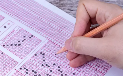 Mano con lápiz completando un examen de respuestas múltiples. ¿Cuántas preguntas son el examen de conducir?
