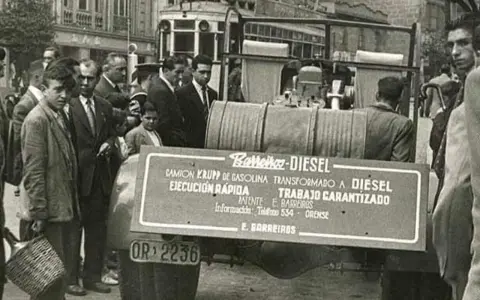 Un camión Barreiros-Diesel, transformado de gasolina, exhibido en la calle. Un grupo de hombres observa la innovación.