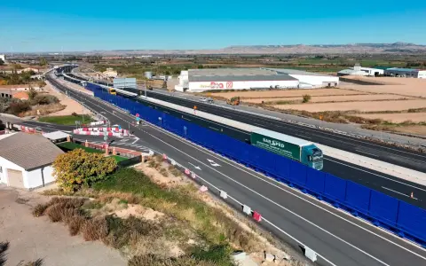 Camión de SAR SPED circula por la a68 autovía, con barreras acústicas azules y paisaje rural al fondo.