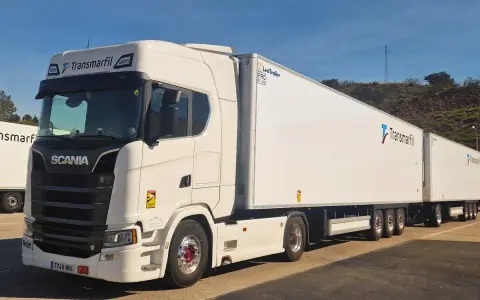 Un mega camión blanco Scania con dos remolques largos de Transmarfil, listo para transportar mercancías.