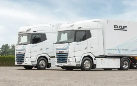 Dos camiones DAF XG Plus eléctricos, blancos, con el interior visible. Uno lleva un remolque DAF.