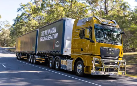Camión amarillo brillante de MAN en carretera, con el lema "The New MAN Truck Generation". Ideal para mostrar que pueden circular los camiones los domingos.
