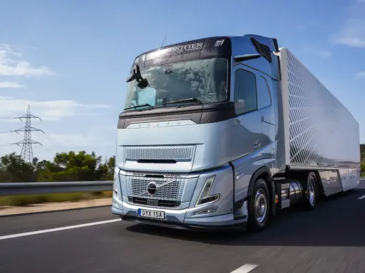 El nuevo Volvo FH Aero, un camión azul metálico, avanza por una carretera soleada, listo para transportar cargas con su diseño aerodinámico.