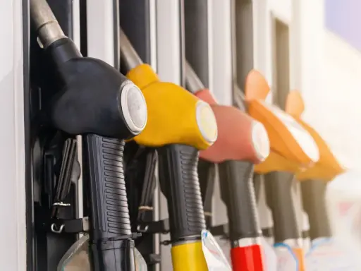 Mangueras de gasolinera en fila, listas para llenar el tanque y promover el ahorro de combustible.