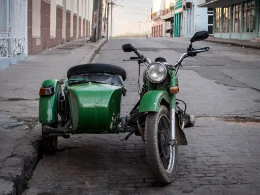 Motocicleta verde con sidecar, lista para recorrer calles empedradas. Un clásico que aún recibe permiso a motocicletas con sidecar.